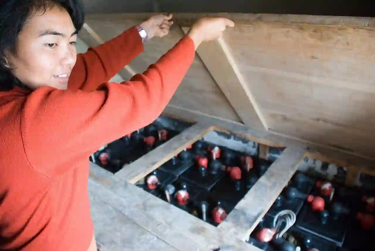 Inspection of batteries in an enclosure Person opening a wooden enclosure containing used batteries
